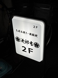 japanese restaurant sign, illuminated at night, directing patrons to the second floor 2F