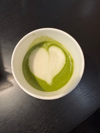 top view of a macha latte in a paper cup with a heart shape on top