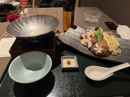 Side view of dinner, aluminium plate on a spiritus cooker, plate with soup ingredients, bowl to drink from and large ceramic spon