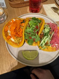 three soft shell tacos with assorted ingredients arranged like a rainbow