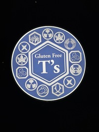 Round restaurant sign, white on blue with black background, Gluten Free T’s in the middel, various small emblems on the outside