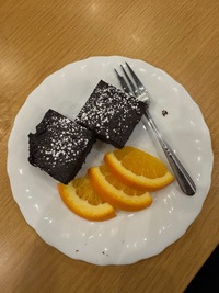 top view of two chocolate cake pieces with sugar dusting and three orange slices