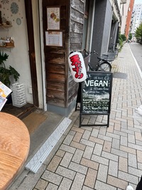 sidewalk and restaurant entrance with street sign advertising vegan food