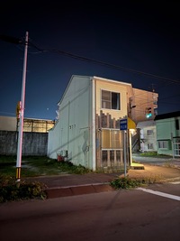 A very narrow standalone house at a street corner at night