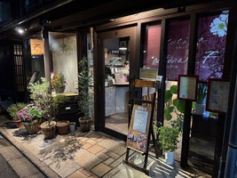 Dark wood panelled restairant entrance framed with various flowers, at night with spot lighting