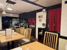 small restaurant interior, white walls with dark brown wood support beams, red curtains and half open kitchen