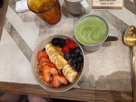 fruit on top of a muesly bowl and macha latte