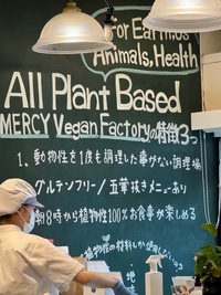 restaurant sign advertising all plant based vegan food in english and japanese