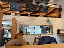 restaurant interior, ground floor has a half-open kitchen with an open second floor seating area up top. White washed stone walls and wooden interor accents